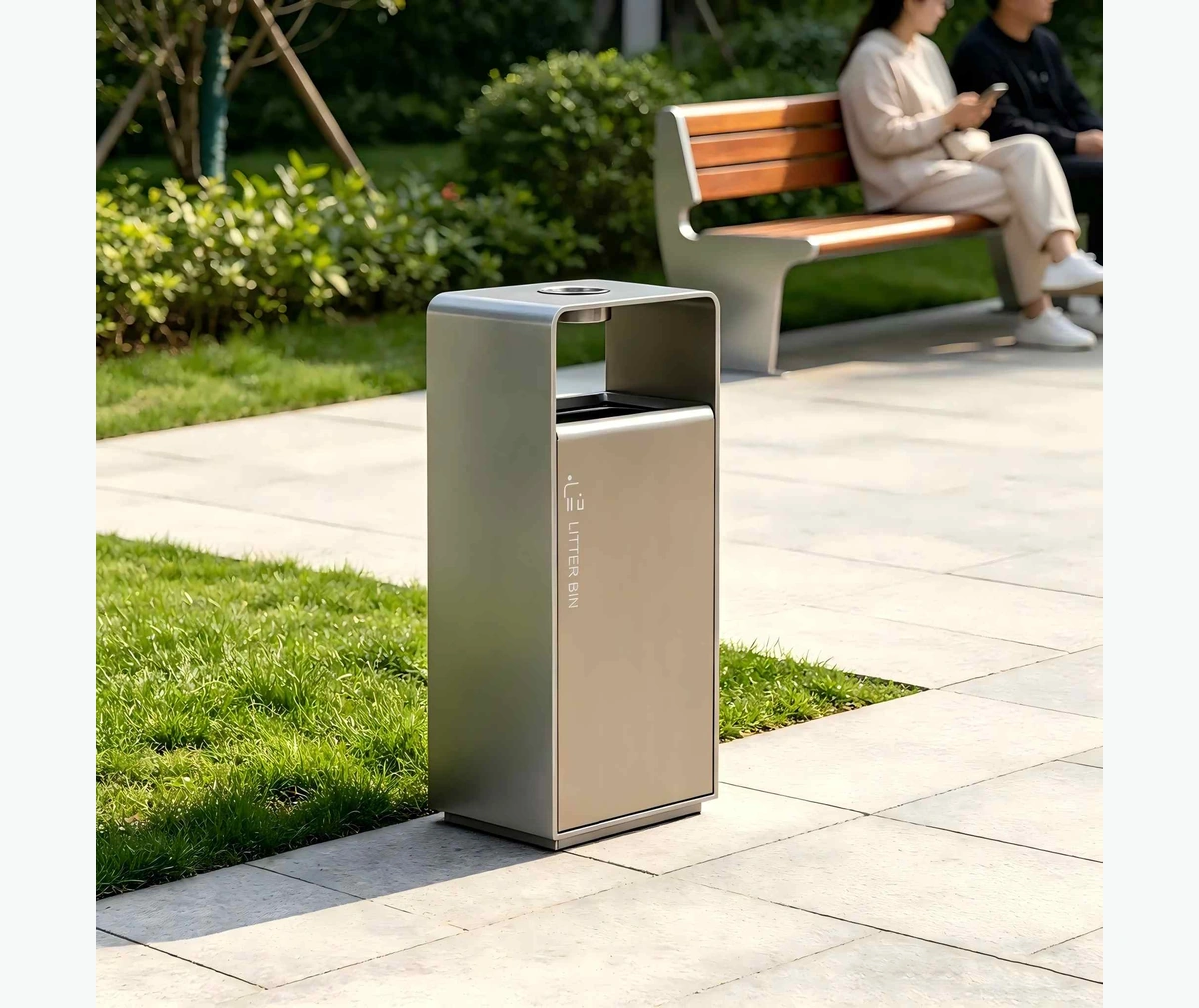 OTX-02C style plain metal outdoor trash receptacle beside a landscaped commercial building entrance.webp